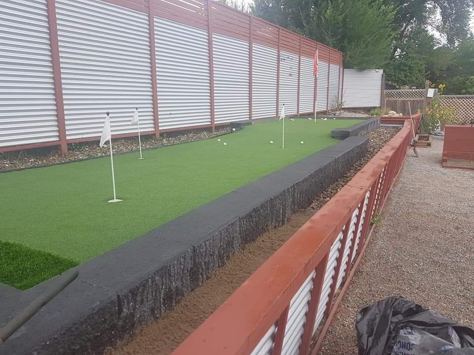 Corrugated metal privacy fence with a red cedar frame beside an artificial putting green