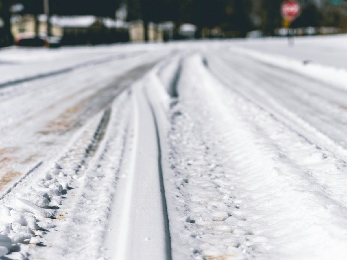 Snow-covered private road with vehicle tracks through it in the North Okanagan